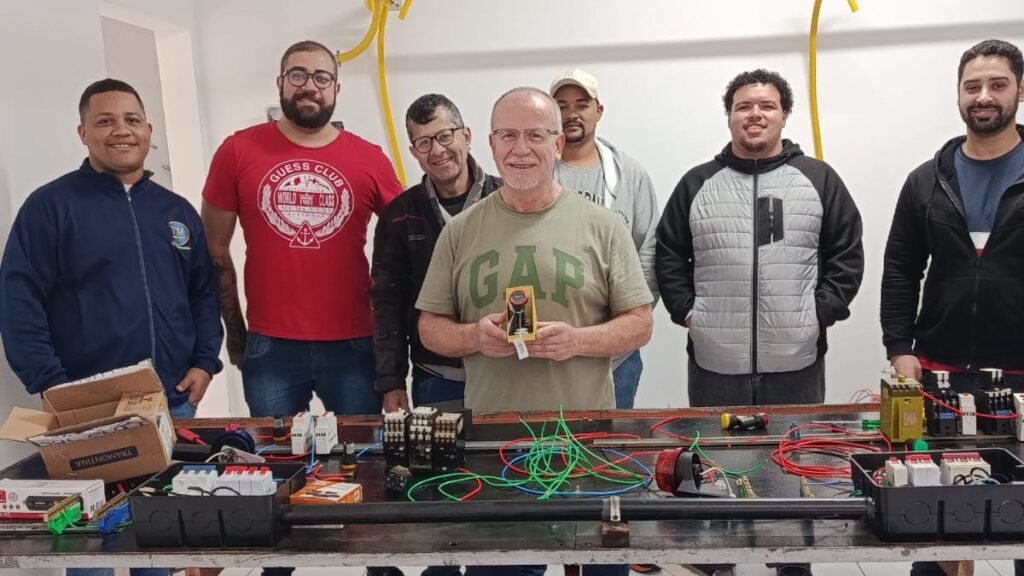 Turma de curso de eletricista na bancada de prÃ¡tica da Escola Piping