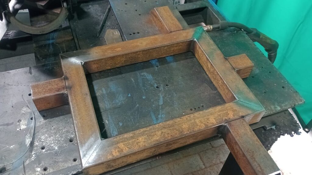 Aluno de traÃ§ado de caldeiraria montando quadro metÃ¡lico na oficina da Escola Piping